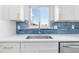 Bright kitchen featuring a stainless steel sink, modern white cabinets, blue backsplash, and quartz countertops at 6500 W 32Nd Ave, Wheat Ridge, CO 80033