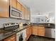 Modern kitchen with granite counters, stainless steel appliances, and dark tile flooring, in open concept design at 9019 E Panorama Cir # D204, Englewood, CO 80112