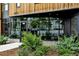 Modern condo entrance with glass windows reflecting surrounding trees, framed by green shrubs and the building number at 1601 Park Ave # 212, Denver, CO 80218