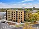 Modern four-story condo building boasts natural wood cladding and balconies, set against a blue sky with autumn foliage at 1601 Park Ave # 212, Denver, CO 80218