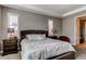 Comfortable main bedroom featuring a tray ceiling, plush bedding, and a cozy red accent chair at 25144 E Archer Pl, Aurora, CO 80018