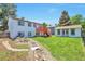 Backyard view featuring lush green grass, stone path, and deck attached to house at 9135 W Maplewood Ave, Littleton, CO 80123