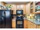 Warm kitchen with wood cabinets, granite countertops, and black appliances, creating a cozy cooking space at 15501 E 112Th Ave # 20C, Commerce City, CO 80022