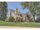 A multi-level condo building featuring brick and wood accents, set amidst a well-maintained lawn and mature trees at 13704 E Lehigh Ave # D, Aurora, CO 80014