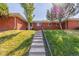 Well-maintained front yard with lush lawn, mature trees, and a welcoming walkway at 6490 E Dakota Ave, Denver, CO 80224
