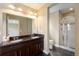 Bathroom featuring double sinks, granite countertops, tiled floors and a glass door shower at 5434 N Xenia St, Denver, CO 80238