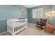 Calming Bedroom features soft blue walls, a white crib, and a comfortable rocking chair at 2587 Foothills Canyon Ct, Highlands Ranch, CO 80129