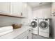 Bright laundry room featuring white cabinetry, quartz countertops, and modern washer and dryer at 853 Stagecoach Dr, Lafayette, CO 80026