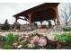 An outdoor kitchen with stone accents under a covered patio, surrounded by lush landscaping at 853 Stagecoach Dr, Lafayette, CO 80026