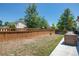 Spacious backyard with a wood fence, grass, trees and a patio seating area, perfect for outdoor activities at 5033 Goshawk Ct, Brighton, CO 80601