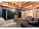 Partially finished basement featuring exposed beams and ductwork, a television, and seating arrangements at 5033 Goshawk Ct, Brighton, CO 80601