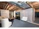 Partially finished basement featuring exposed beams and ductwork, a fridge, television and seating arrangements at 5033 Goshawk Ct, Brighton, CO 80601