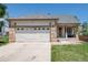 Charming home featuring a two-car garage with stylish brick accents, a covered porch and a well-kept lawn at 5033 Goshawk Ct, Brighton, CO 80601