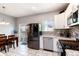 Open-concept kitchen with stainless steel appliances, white cabinets, and a view to the dining area and backyard at 5033 Goshawk Ct, Brighton, CO 80601