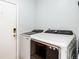 Modern laundry room featuring new Samsung washer and dryer units with bronze accents, and a white entry door at 5033 Goshawk Ct, Brighton, CO 80601