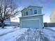Two-story house with light blue siding, attached garage, and snowy front yard at 1090 Quail Cir, Brighton, CO 80601
