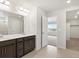 Bright bathroom featuring dual sinks, a large mirror, and access to the bedroom at 17424 E 90Th Pl, Commerce City, CO 80022