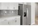 Bright kitchen features stainless steel refrigerator and white cabinetry with stylish backsplash at 17424 E 90Th Pl, Commerce City, CO 80022