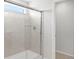 Modern bathroom shower with glass door, tiled walls, and a convenient transom window for natural light at 17424 E 90Th Pl, Commerce City, CO 80022