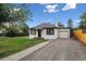 View of exterior showing the well kept lawn and a one car garage with a gravel driveway at 11842 W 14Th Ave, Lakewood, CO 80401