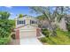 A home with brick accents, a two-car garage, mature trees and landscaping under a bright blue sky at 8441 S Timberwood St, Highlands Ranch, CO 80126