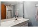 Clean bathroom with white sink, single faucet, and framed mirror with opened shower behind it at 8293 S Reed St, Littleton, CO 80128