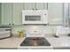 Close-up of the kitchen features a smooth cooktop, microwave, window, and light colored cabinets at 2420 E 127Th Ave, Thornton, CO 80241