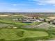 Aerial view of the golf course, featuring lush green fairways, sand traps, and a scenic pond at 16448 E 111Th Pl, Commerce City, CO 80022