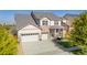 Two-story home featuring a three-car garage, stone accents, and a well-manicured front yard at 6577 S Kewaunee Way, Aurora, CO 80016