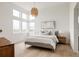 Light-filled main bedroom with light wood floors, a large bed, and ample windows at 5831 Galena St, Denver, CO 80238