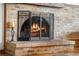 A large brick fireplace with a metal screen and burning logs at 5115 Bristol St, Arvada, CO 80002