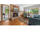 A cozy living room with brick fireplace and hearth, hardwood floors and a beautiful view out of the large window at 5115 Bristol St, Arvada, CO 80002