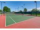 Outdoor tennis court with a net and lights surrounded by a fence in a well-maintained community at 10672 Wintersweet Pl, Parker, CO 80134