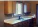 Galley kitchen featuring a stainless-steel sink, tiled countertops and wood cabinets at 671 Brentwood St, Lakewood, CO 80214