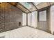 Bright sunroom with brick wall, tile flooring, skylights, and natural light streaming through sheer curtains at 671 Brentwood St, Lakewood, CO 80214