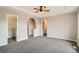 Main bedroom with ceiling fan, arched entryways to closet and bathroom, and neutral walls at 10626 Cherrybrook Cir, Highlands Ranch, CO 80126