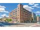 Full exterior shot of the brick building with many windows on a sunny day, located at a street corner at 1863 Wazee St # 6B, Denver, CO 80202
