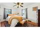 Cozy bedroom featuring a decorative ceiling fan, hardwood floors, and bright natural lighting through the windows at 4315 S Elati St, Englewood, CO 80110
