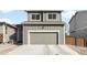 A two-car garage with gray siding and white trim sits at the end of a concrete driveway at 1103 Spartan Ave, Berthoud, CO 80513