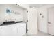 Bright laundry room features a white washer and dryer, wire rack shelving, and a modern white door at 1103 Spartan Ave, Berthoud, CO 80513