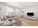 Inviting living room with a plush gray sectional sofa, large windows, and modern entertainment center at 1103 Spartan Ave, Berthoud, CO 80513