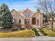 Charming brick home boasts an inviting entrance, complemented by mature trees and manicured landscaping at 7425 S Utica St, Littleton, CO 80128
