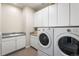 Laundry room with white cabinets, utility sink, and modern washer and dryer at 7425 S Utica St, Littleton, CO 80128