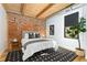 Bright bedroom with exposed brick wall, wood ceiling beams, and plush bedding at 3260 Curtis St, Denver, CO 80205