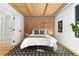 Spacious bedroom with exposed brick wall, wood ceiling beams, and hardwood floors at 3260 Curtis St, Denver, CO 80205