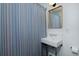 Bright bathroom featuring a classic sink, a wooden-framed mirror, and a striped shower curtain for a clean aesthetic at 747 N Downing St, Denver, CO 80218