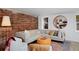 Stylish living room featuring a comfortable sectional sofa, exposed brick wall, and a unique round mirror at 747 N Downing St, Denver, CO 80218