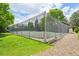 View of the community tennis court, surrounded by green lawn and tall trees on a sunny day at 7474 E Arkansas Ave # 13-02, Denver, CO 80231