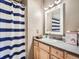 Cozy bathroom with blue striped shower curtain, white vanity, and modern lighting at 13517 Clayton Ct, Thornton, CO 80241