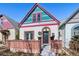 A bright exterior, accented by pink and turquoise trim, features a brick foundation and a black front door at 69 W Cedar Ave, Denver, CO 80223